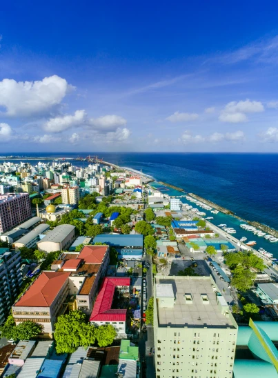 an aerial view of a city next to the ocean, maldives in background, slide show, high-quality photo