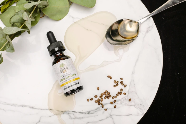 a white plate topped with coffee beans next to a spoon, snake oil, hemp, shades of gold display naturally, product image