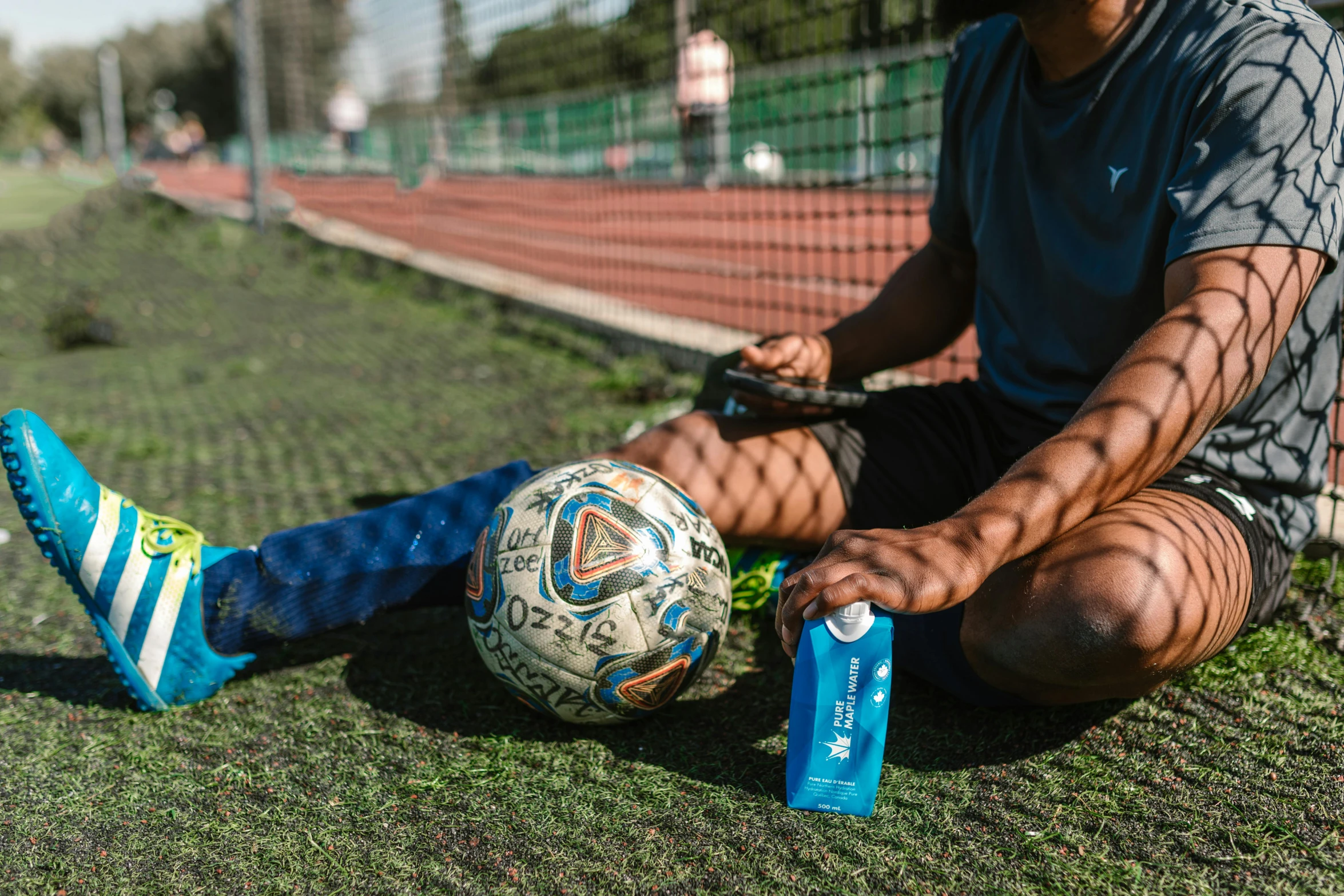 a man sitting on the ground with a soccer ball, blue themed, paddle and ball, instagram post, shot with sony alpha 1 camera