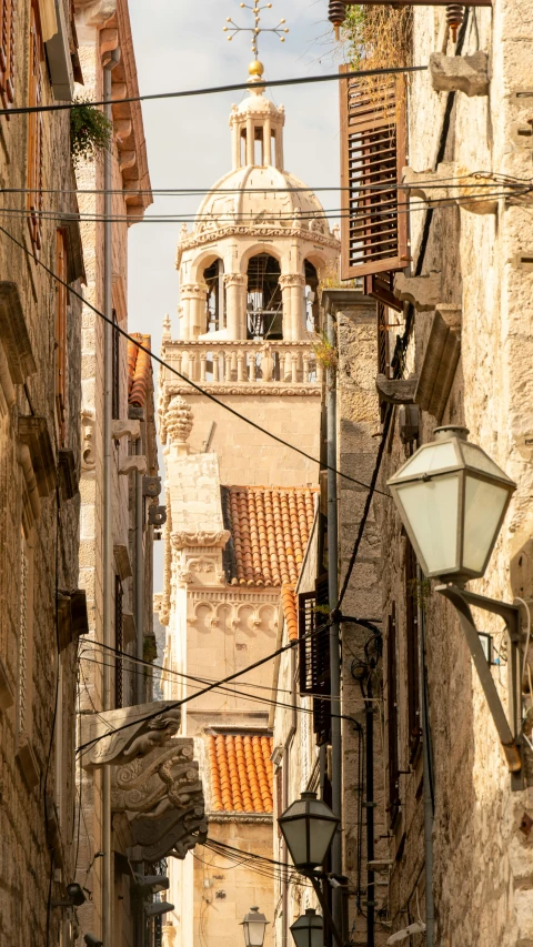 a narrow street with a clock tower in the background, by Matija Jama, shutterstock, romanesque, ivory and copper, square, domes, light from top right