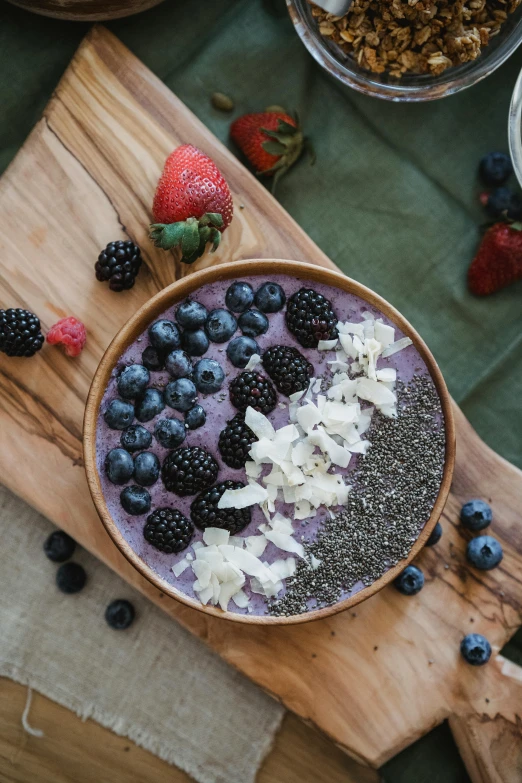 a bowl of fruit sitting on top of a wooden cutting board, purple, mecca, vanilla smoothie explosion, botanicals