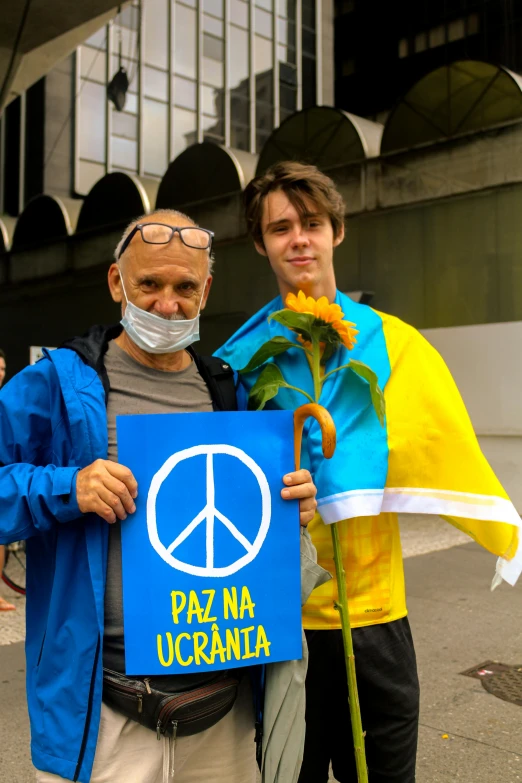 two people standing next to each other holding a sign, a photo, inspired by László Paál, antipodeans, peace sign, in blue and yellow clothes, two young men, in sao paulo