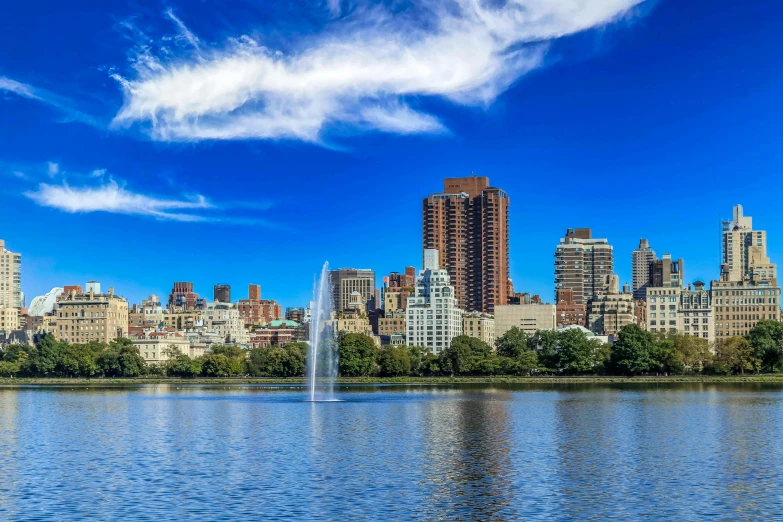 a large body of water with buildings in the background, pexels contest winner, hudson river school, a park, clear blue skies, promo image, background : diego fazio