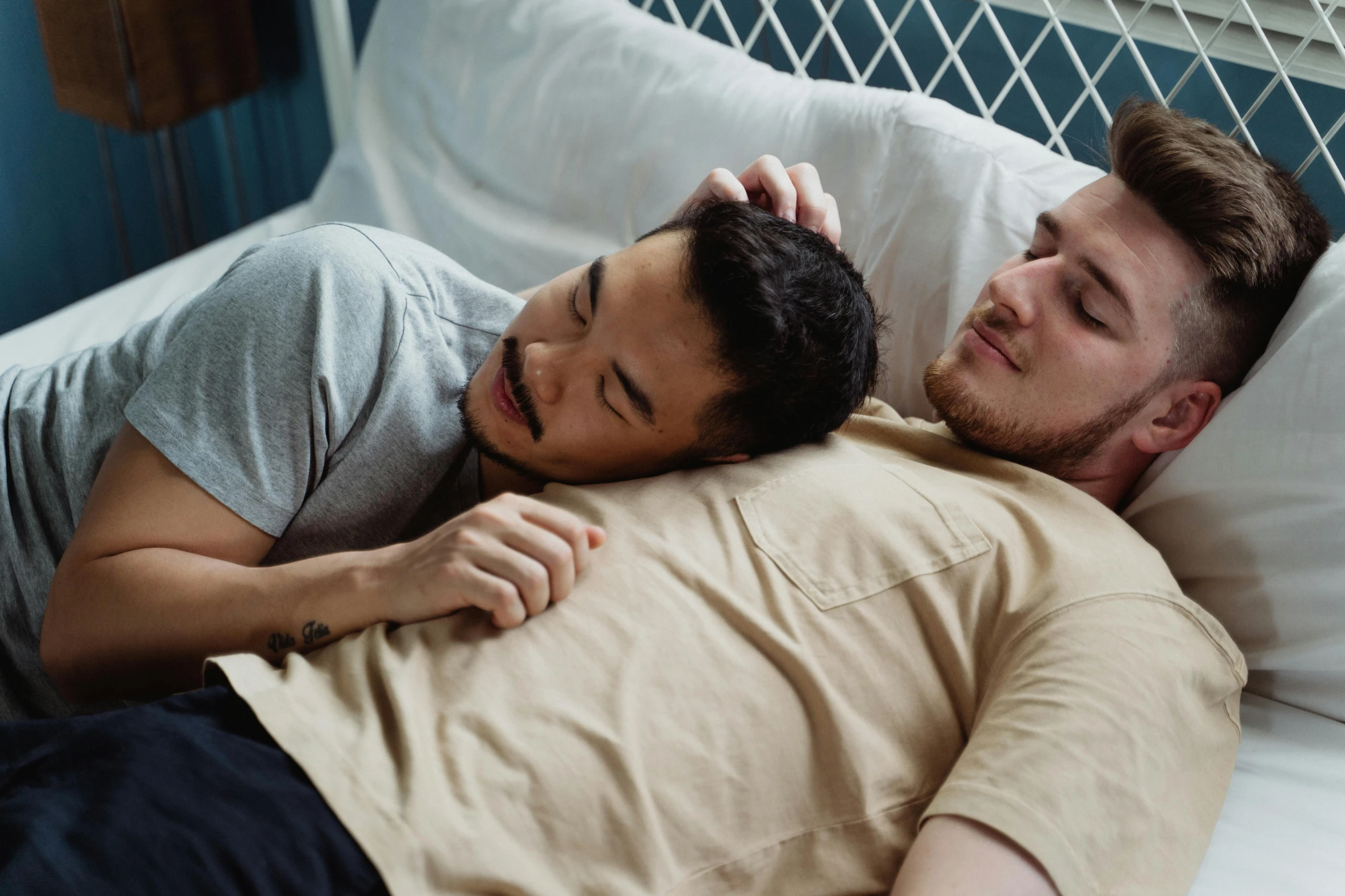 a couple of men laying on top of a bed, trending on pexels, lgbt, ruan jia and brom, gentle expression, owen klatte