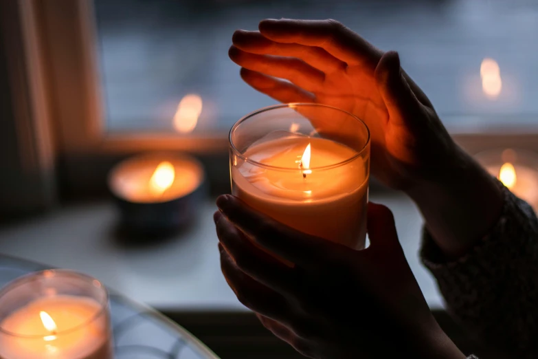 a person holding a lit candle in front of a window