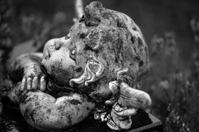 a black and white photo of a statue of an elephant, a statue, unsplash, baroque, dead child, cherub, close-up photo, lying