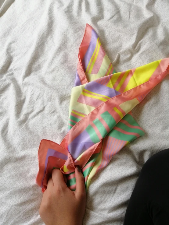 a person tying a tie on top of a bed, colorful bandana, pastel colours overlap, 1980s, soft translucent fabric folds