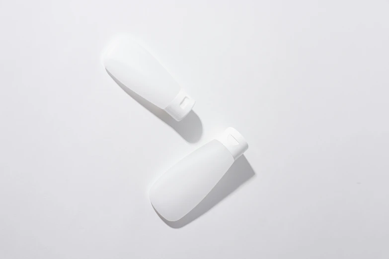 two white plastic bottles sitting on top of a white surface, sleek streamlined design, spoon, thumbnail, lumi