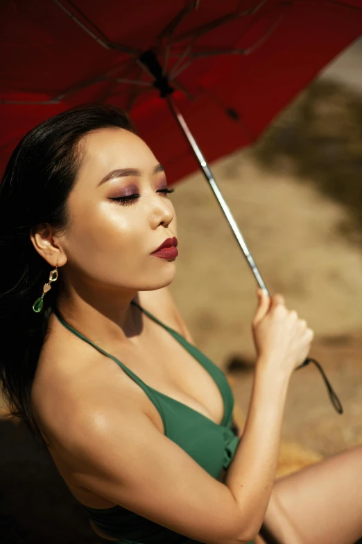 a woman in a green bikini holding a red umbrella, an album cover, trending on pexels, asian beautiful face, sun drenched, profile image, lipstick