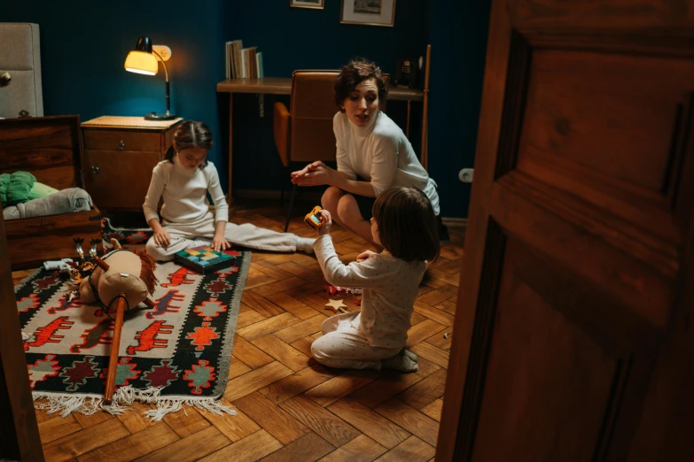 a woman and two children sitting on the floor, by Adam Marczyński, pexels contest winner, arts and crafts movement, gaming room, in the bedroom at a sleepover, an escape room in a small, profile image