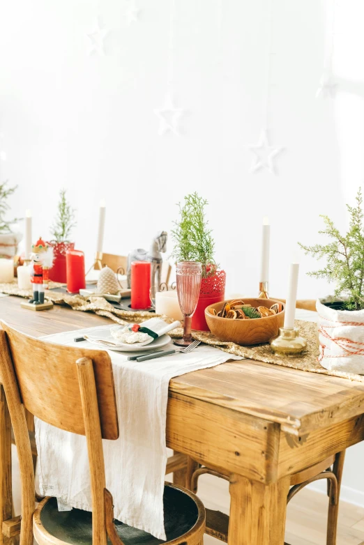 a wooden table topped with wooden chairs next to a white wall, inspired by Ernest William Christmas, trending on pexels, wearing festive clothing, food stylist, red flags holiday, natural materials