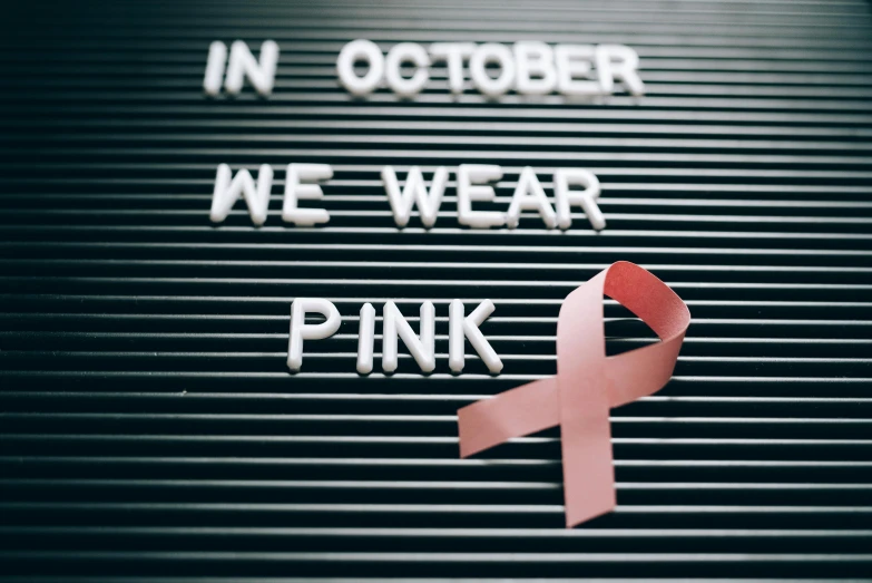 a sign that says in october we wear pink, a photo, pexels, white ribbon, instagram photo, ap news photo, on display