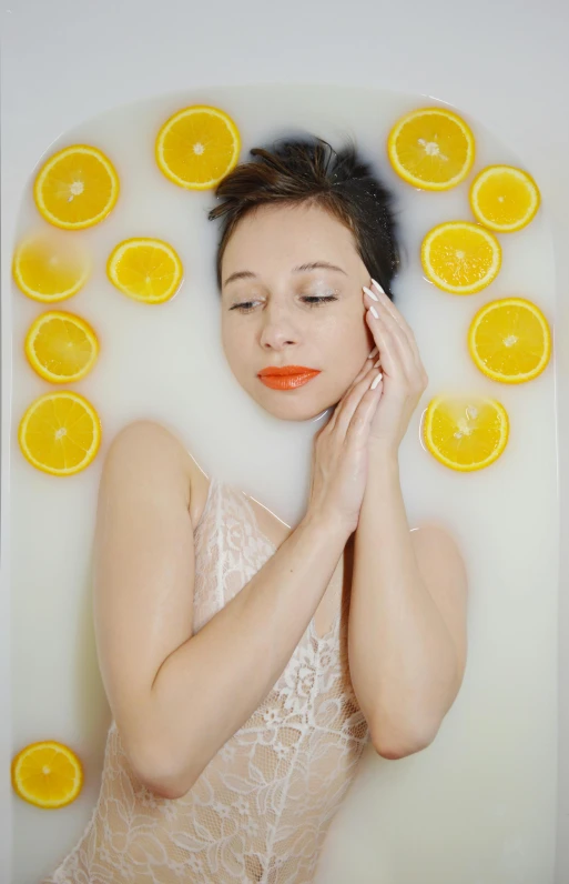 a woman laying in a bath filled with orange slices, inspired by Bert Stern, pexels, demur, square, lemons, candy treatments