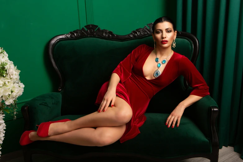 a woman in a red dress sitting on a green couch, bulgari style, meni chatzipanagiotou, high quality photo, low cut dress