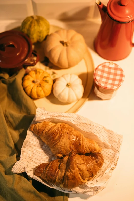 a table topped with croissants and pumpkins, a still life, unsplash, background image, high angle shot, digital image