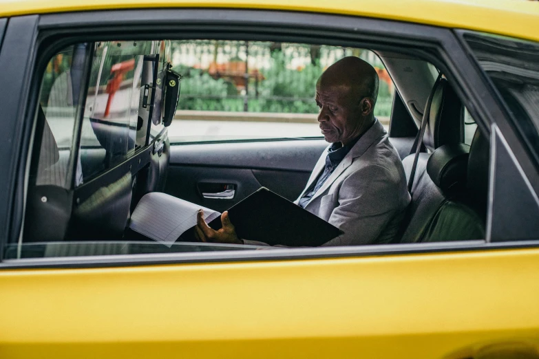 a man sitting in the passenger seat of a yellow car, lance reddick, in new york city, patrick stewart, nat geo