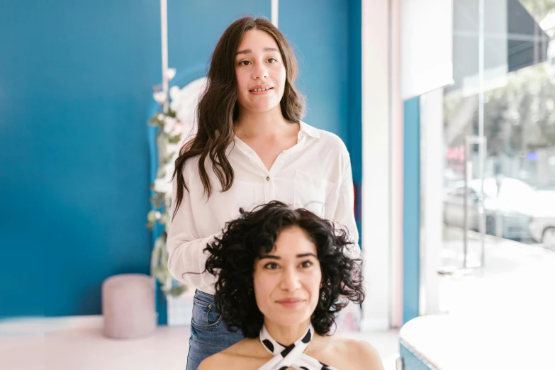 a woman getting her hair done by a hair stylist, a portrait, by Olivia Peguero, trending on unsplash, renaissance, with blue skin, two women, portrait pose, facing front