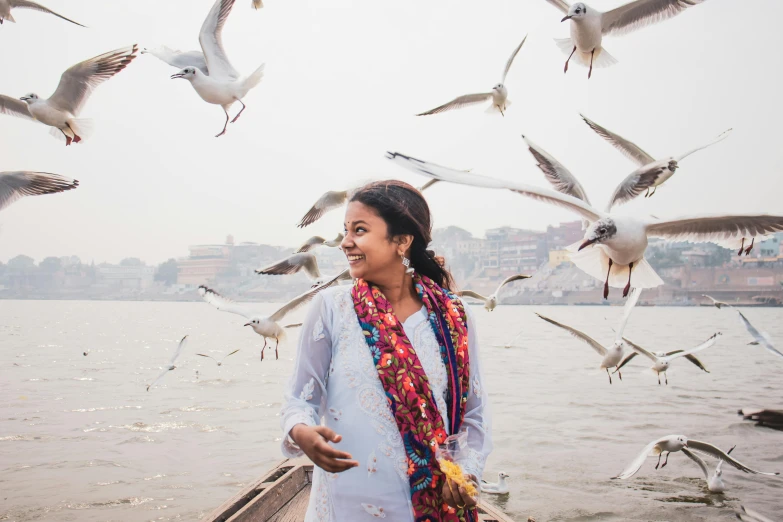 a woman standing on a boat surrounded by seagulls, by Ke Jiusi, pexels contest winner, happening, indian girl with brown skin, she is smiling and excited, river with low flying parrots, alana fletcher