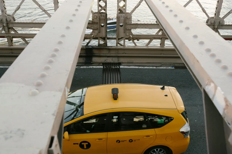 a yellow taxi cab driving across a bridge, unsplash, happening, high angle shot, mechanical superstructure, nyc, low quality photo