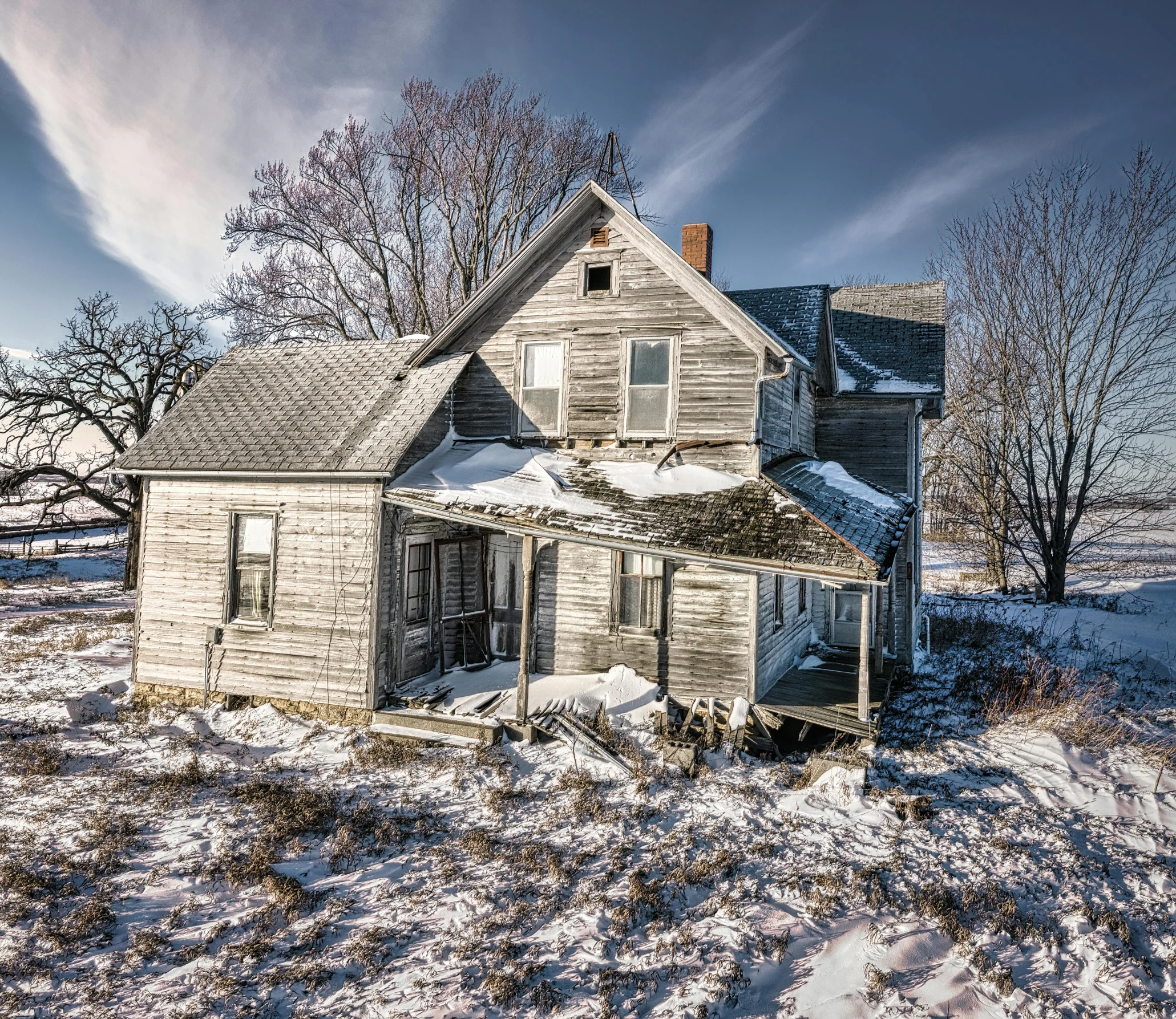 an old house sitting in the middle of a snow covered field, a colorized photo, pexels contest winner, photorealism, dressed in a worn, midwest town, wide high angle view, interstellar hyper realism