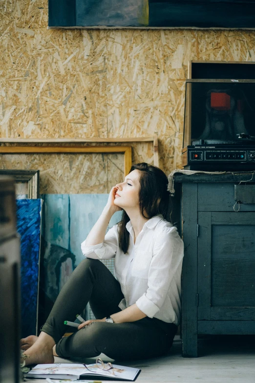 a woman sitting on the floor in front of a tv, inspired by Elsa Bleda, pexels contest winner, arbeitsrat für kunst, in a warehouse, portrait of a female art student, profile pic, promo image