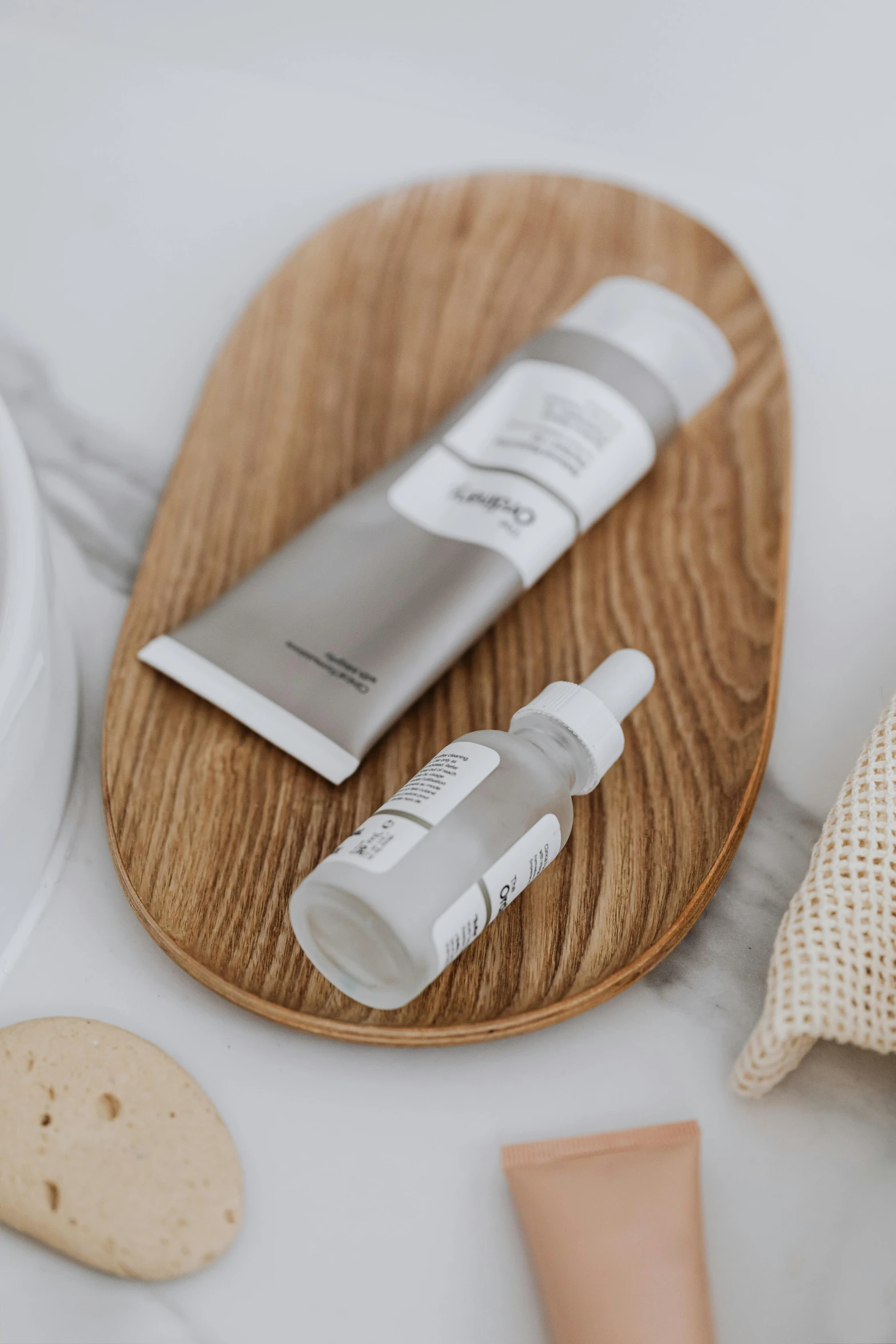 a bottle of lotion sitting on top of a wooden tray, a picture, unsplash, dau-al-set, with grey skin, silicone skin, gray canvas, white and silver