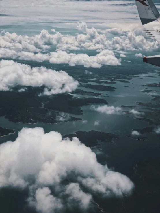 the wing of an airplane flying over a body of water, by Jessie Algie, pexels contest winner, sitting in a fluffy cloud, floating islands, hd footage, loots of clouds