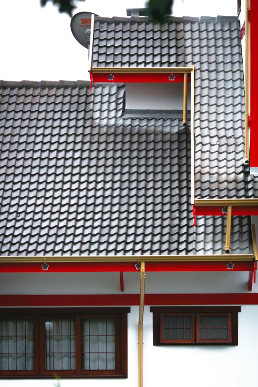 a cat sitting on a window sill in front of a house, inspired by Itō Jakuchū, unsplash, mingei, black steel with red trim, intricate detailed roof, south jakarta, seen from straight above