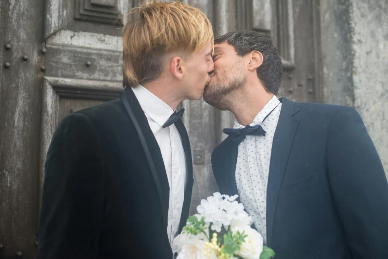 a couple of men standing next to each other, kissing, well decorated, in doors, profile image