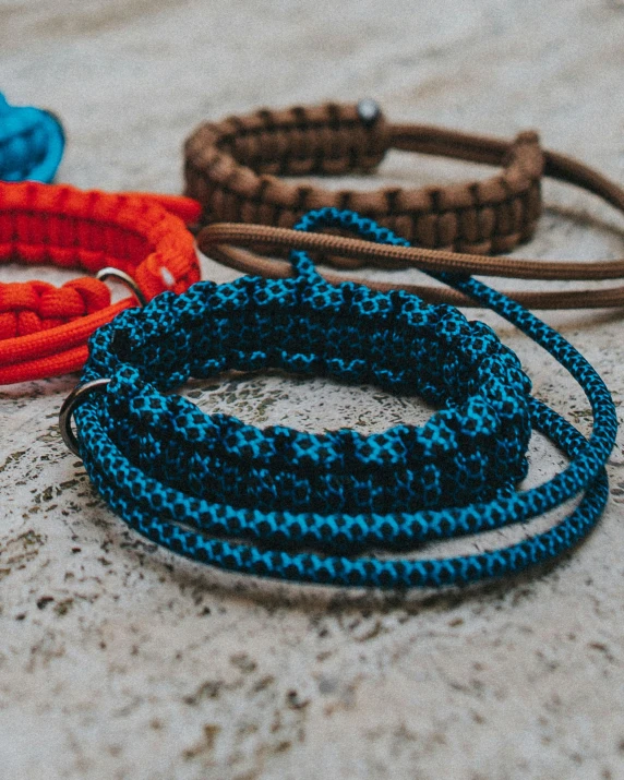 a couple of bracelets sitting on top of a cement floor, by Nina Hamnett, unsplash, collar and leash, cerulean blue and burnt sienna, extreme close up shot, webbing