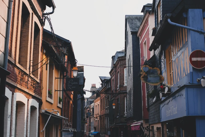 a group of people walking down a street next to tall buildings, by Andrée Ruellan, pexels contest winner, renaissance, french village exterior, normandy, red - yellow - blue building, back alley