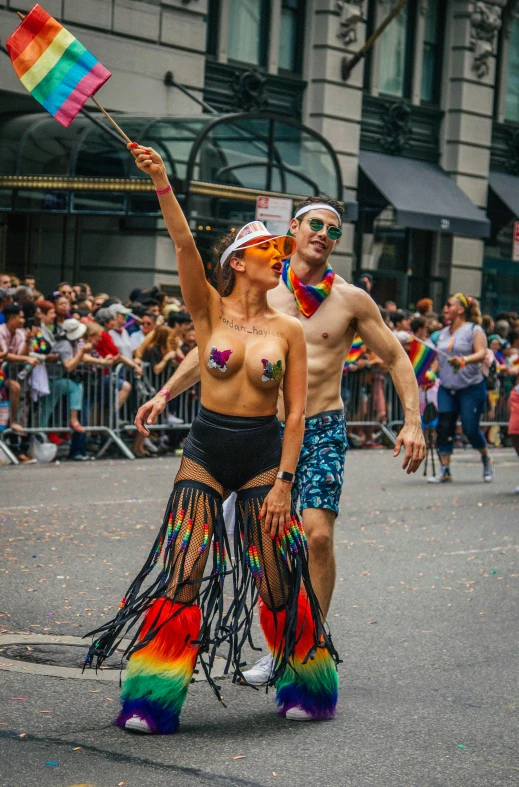 a couple of people that are walking in the street, by Meredith Dillman, pexels contest winner, pride parade, scantily clad, in a jumping float pose, she has feathers