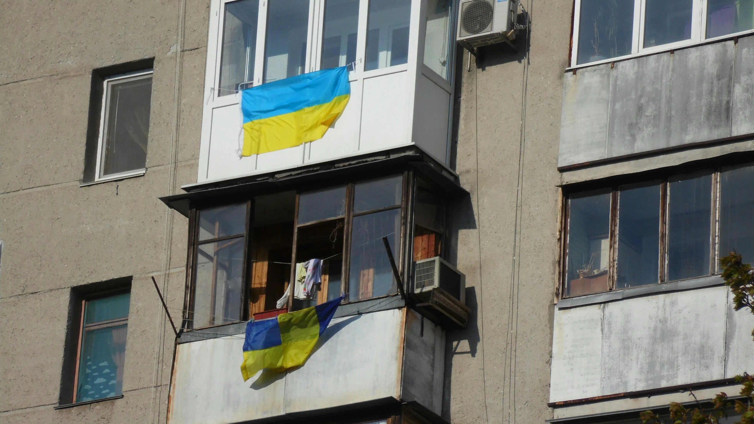 a building with a flag on the side of it, a photo, by January Suchodolski, ukrainian, sitting on a window sill, unedited, square