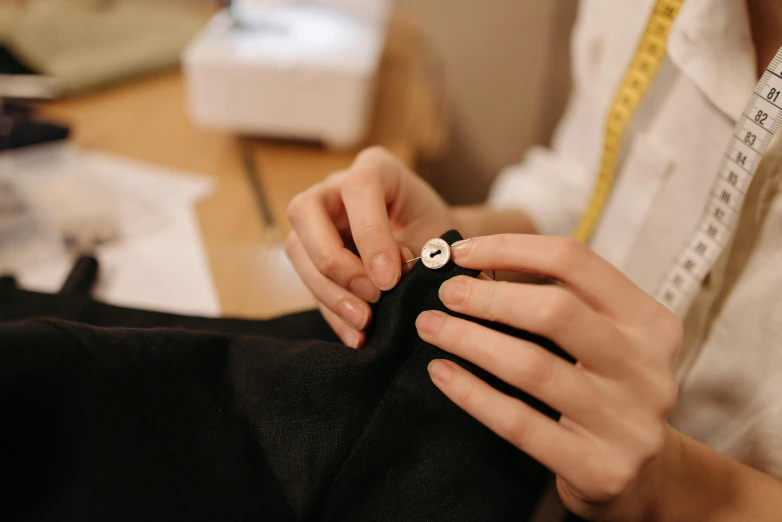 a close up of a person using a sewing machine, wearing a black suit, wolfy nail, thumbnail, wearing lab coat and a blouse