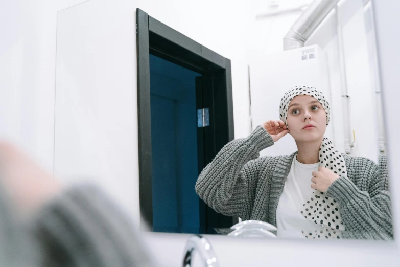 a woman brushing her teeth in front of a mirror, inspired by Louisa Matthíasdóttir, trending on pexels, wearing a head scarf, stood in a lab, shaved, grey clothes