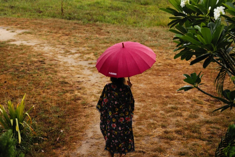 a woman walking down a dirt path holding a pink umbrella, by Lucia Peka, unsplash, visual art, sri lanka, maroon red, after the rain, instagram post