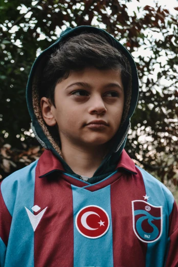 a young boy standing in front of a tree, an album cover, pexels contest winner, hurufiyya, football mascot, turkey, magenta and crimson and cyan, in a hoodie