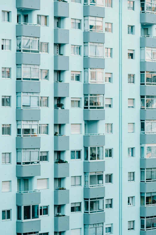 a tall building with lots of windows and balconies, inspired by Elsa Bleda, pexels contest winner, pastel blue, neighborhood, teal aesthetic, blue and grey