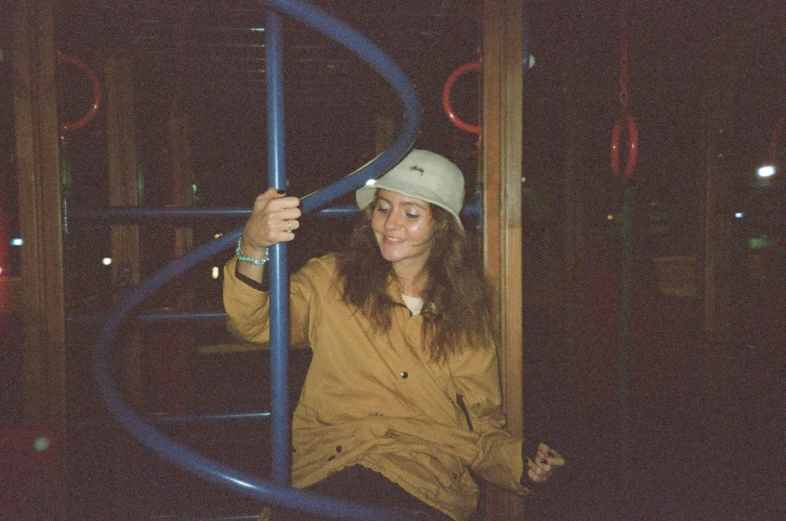 a woman in a hard hat sitting on a playground structure, an album cover, inspired by Elsa Bleda, low quality photo, night time, grainy, smiley