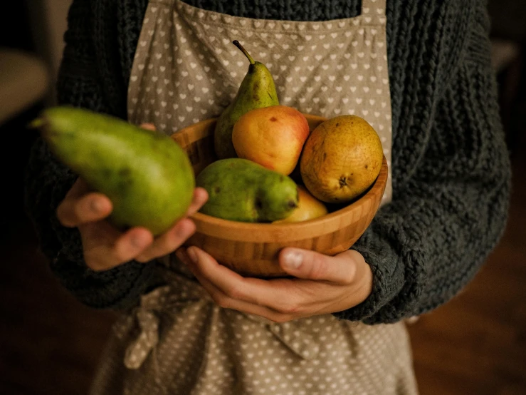 a woman in an apron holding a bowl of fruit, a still life, pexels contest winner, pears, wooden bowl, thumbnail, casually dressed