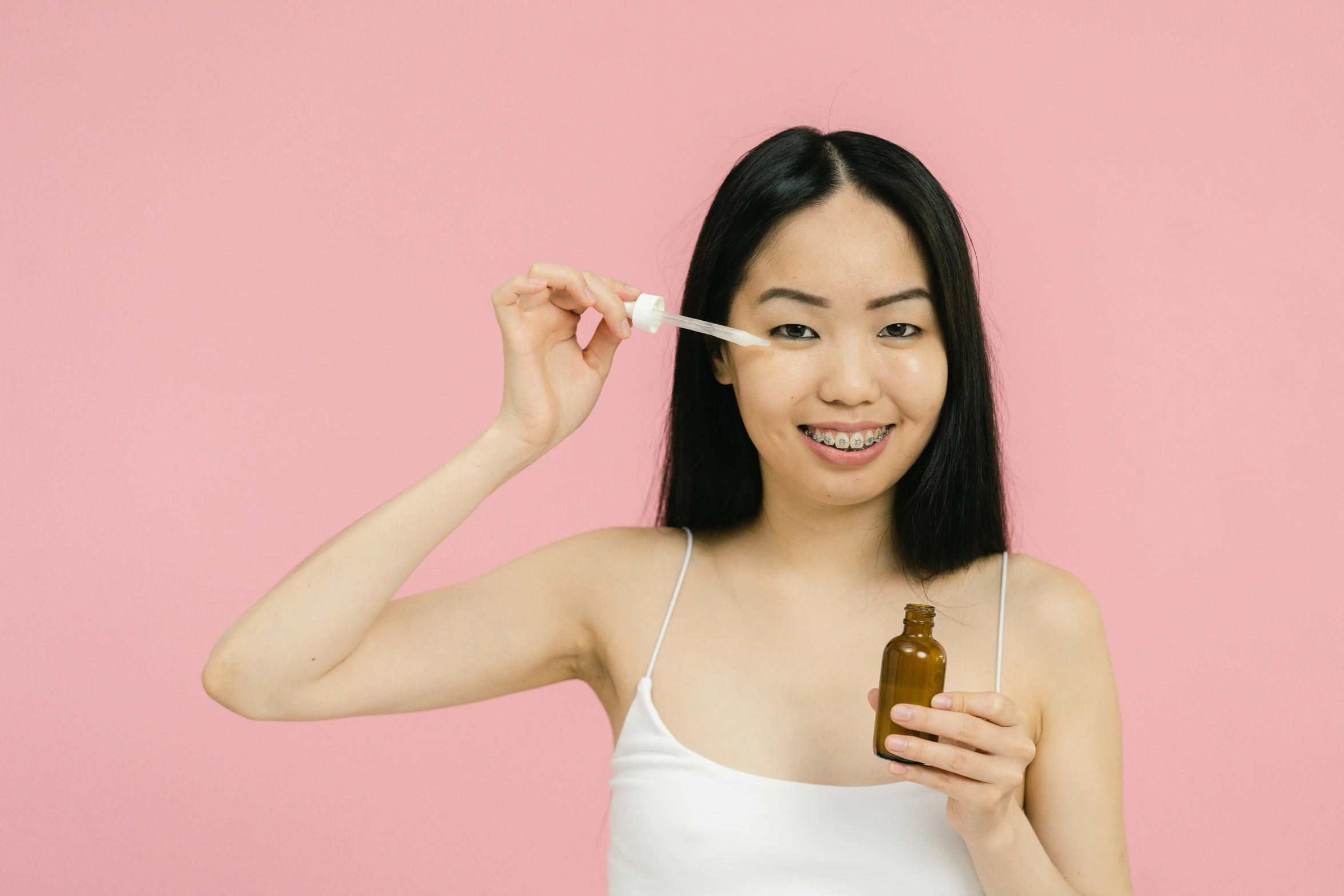 a close up of a person holding a bottle of liquid, a picture, trending on pexels, detailed face of a asian girl, manuka, pink, woman is curved