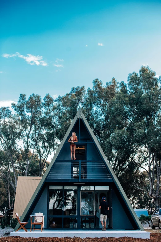 a person sitting on the roof of a house, by Lee Loughridge, unsplash, maximalism, glamping, “ iron bark, full front view, triangle