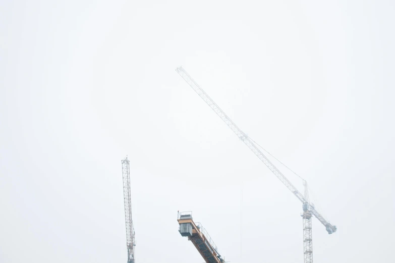 a couple of cranes that are standing in the snow, inspired by Zhang Kechun, pexels contest winner, constructivism, white minimalist architecture, low angle mist, under construction, dan mumfor