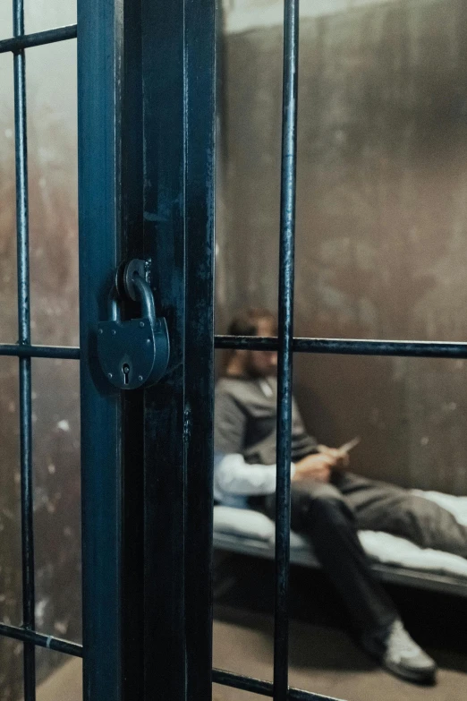 a man sitting on a bed in a jail cell, trending on pexels, professional iphone photo, window, lock, worksafe. instagram photo
