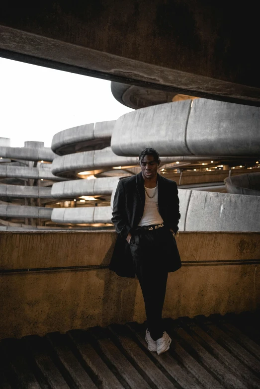 a man standing on top of a wooden floor, by Thomas Fogarty, pexels contest winner, brutalism, set inside of parking garage, album art young thug, wearing black overcoat, riyahd cassiem