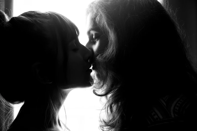 a couple of women kissing each other in front of a window, pexels contest winner, romanticism, black an white, teenage girl, with backlight, portrait shot 8 k