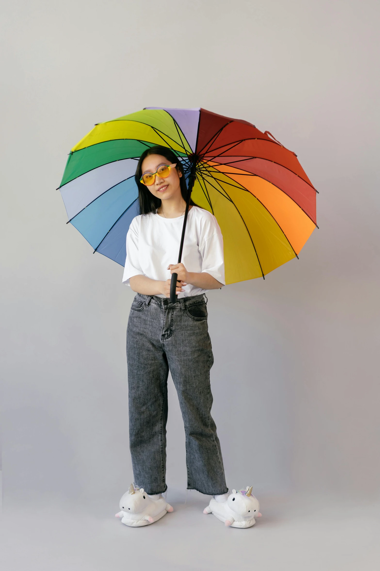 a woman holding a rainbow colored umbrella over her head, a cartoon, trending on unsplash, bauhaus, wearing thin large round glasses, asian women, photographed for reuters, portrait full body