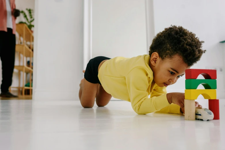 a young child playing with blocks on the floor, pexels contest winner, colors: yellow, african american, crawling on the ground, profile image