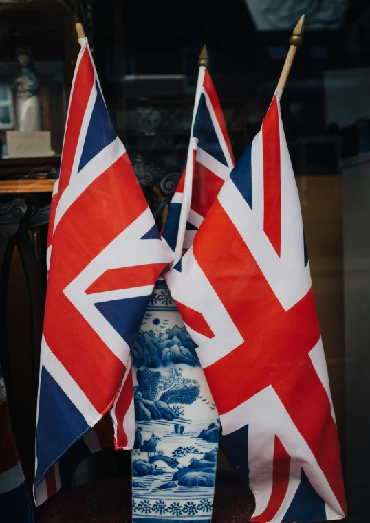 a couple of flags sitting on top of a table, a picture, by Kev Walker, unsplash, shop front, royal photo, 🚿🗝📝