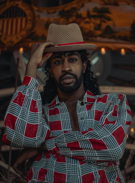 a man with a hat standing in front of a carousel, an album cover, inspired by Theo Constanté, trending on pexels, renaissance, playboi carti portrait, bearded cowboy, ( ( dark skin ) ), square